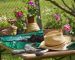 Flowers, hat and gardening tools on table